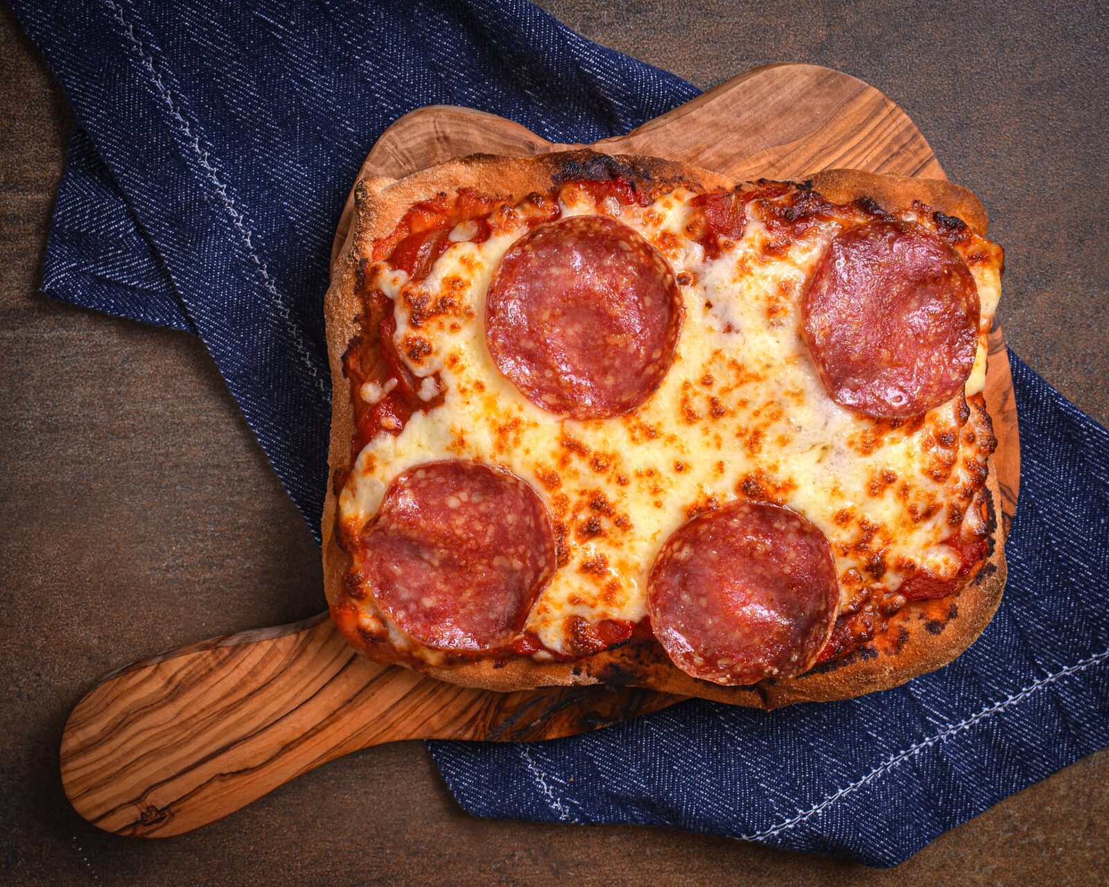 Smolenski’s pepperoni pinsa served on an olive wood board